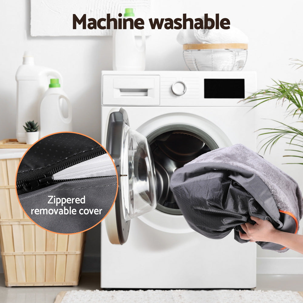 Person placing a gray gog bed cover into a washing machine with text indicating machine washability.